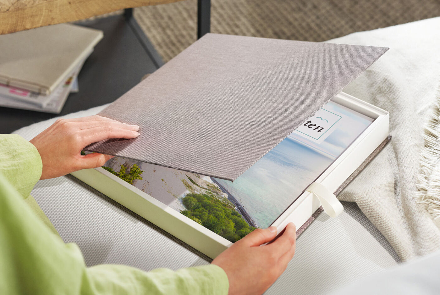Person öffnet eine Geschenkbox mit einem CEWE FOTOBUCH mit Naturmotiv auf dem Einband